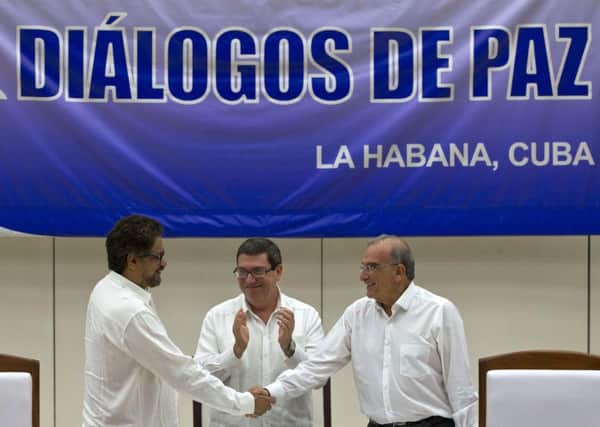 Humberto de la Calle, right, head of Colombia's government peace negotiation team, shakes hands with Ivan Marquez, chief negotiator of the Revolutionary Armed Forces of Colombia, left, while Cuban Foreign Minister Bruno Rodriguez, center, applauds. They had just signed a peace agreement in Havana, Cuba, Wednesday, August 24, 2016