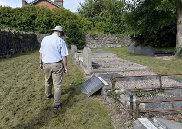 A member of the public inspects his fathers grave after hearing of attack.
 Photograph by Stephen  Hamilton