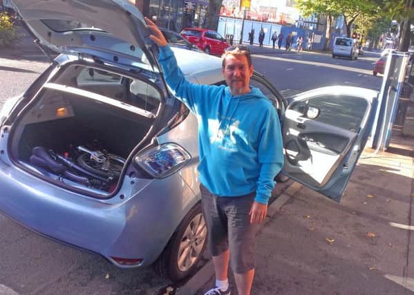 Green Party councillor John Barry charging his car on the Dublin Road in Belfast, and showing his folded bike in the boot