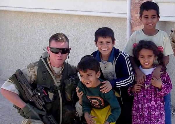 Ryan Gray with the Royal Signals, attached to a Danish troop unit, alongside Iraqi children in November 2005 to the north of Basra.