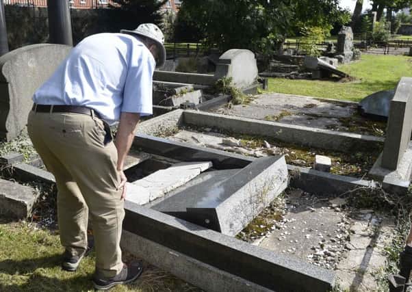 A member of the public inspects his father's grave after hearing of the attack
