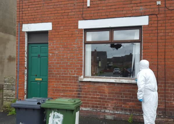 A forensics officer examines what appears to be shot gun damage to a house in Princes Street Lurgan