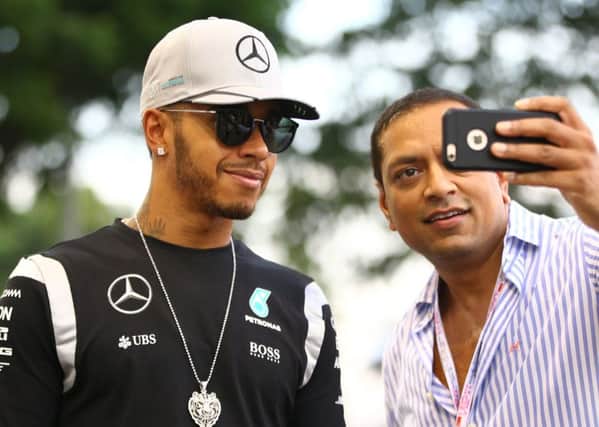 Mercedes driver Lewis Hamilton of Britain poses for a selfie with a fan as he arrives at the Marina Bay City Circuit