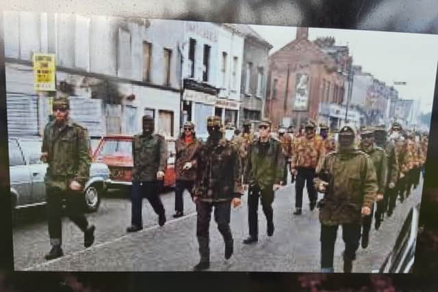 A photo of masked men in paramilitary attire is on the mural