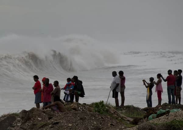 People stand on the coast watching the surf produced by Hurricane Matthew, on the outskirts of Kingston, Jamaica.  (AP Photo/Eduardo Verdugo)