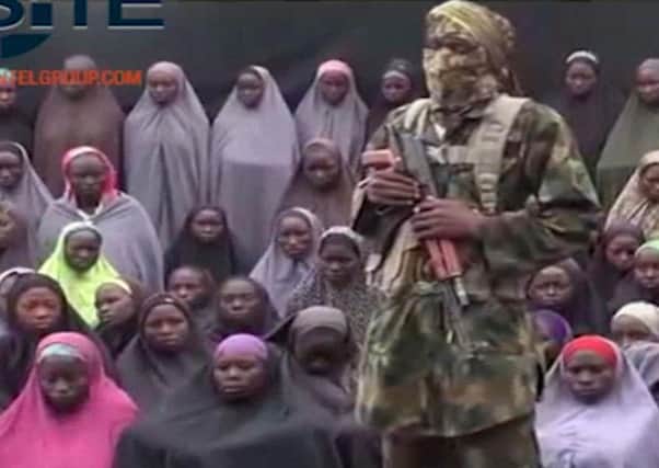 An alleged Boko Haram soldier standing in front of a group of girls alleged to be some of the 276 abducted Chibok schoolgirls held since April 2014, in an unknown location in August 2016.