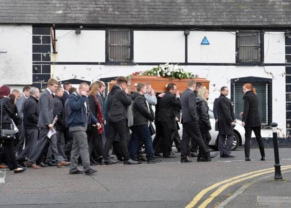 Mourners carry one of the coffins to the funeral in Carmoney