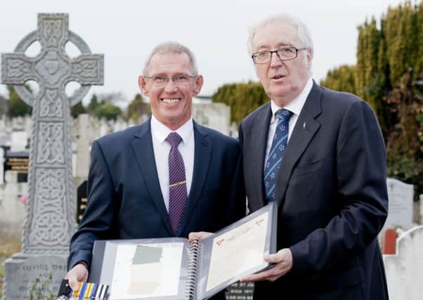 Handout photo dated 11/12/16 issued by Fennell Photography of David Blake, left, great grandson of John Le Provost, and John Green, chairman of Glasnevin Trust, holding a remnant of the Tricolour that flew over one of the frontlines in the 1916 Rising, at the graveside of Dublin tailor Thomas Joseph Meldon in Glasnevin Cemetery. PRESS ASSOCIATION Photo. Issue date: Sunday December 11, 2016. The piece of flag has been in Jersey for the last 100 years after a native of the island and a member of the British Army's Jersey Pals Battalion climbed on to the roof of the Jacob's Biscuit Factory to take it down while under fire from rebel snipers. See PA story HISTORY Tricolour Ireland. Photo credit should read: Iain White/Fennell Photography/PA Wire

NOTE TO EDITORS: This handout photo may only be used in for editorial reporting purposes for the contemporaneous illustration of events, things or the people in the image or facts mentioned in the caption. Reuse of the picture may require further permission from the copy