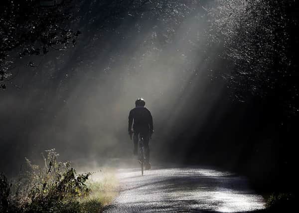 A man cycles through some early morning fog on a country lane near Copthorne in West Sussex.