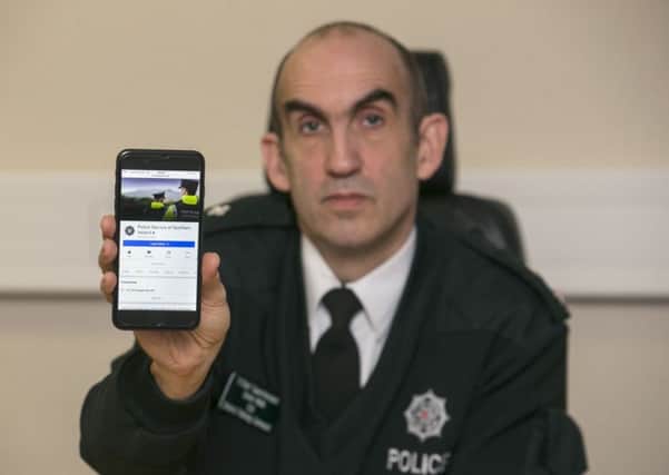 PSNI Chief Superintendent Simon Walls holds up a phone showing the force's Facebook page at the headquarters of the Police Service of Northern Ireland in Belfast. Burglars in Northern Ireland are having empty houses advertised to them by the growing trend of posting holiday snaps on social media, the police commander has warned. See PA story ULSTER Burglary. Photo credit: Liam McBurney/PA Wire