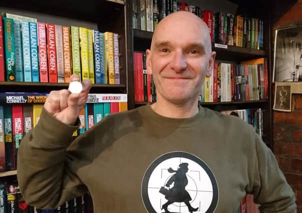 Owner of No Alibis David Torrans with the 50p he received as a joke in response to another booksellers browsing charge
