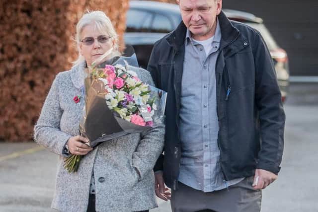 The grandparents of the victim with a floral tribute near Alness Drive in the Woodthorpe area of York, where a teenager was arrested Monday after the death of a seven-year-old girl.