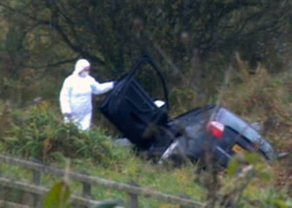 Prison officer David Black's black Audi A4 car lies in a ditch off the M1 motorway this morning after the attack.