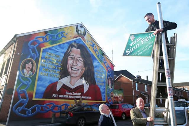 Sinn Fein supporters put up election posters on the Falls Road, west Belfast