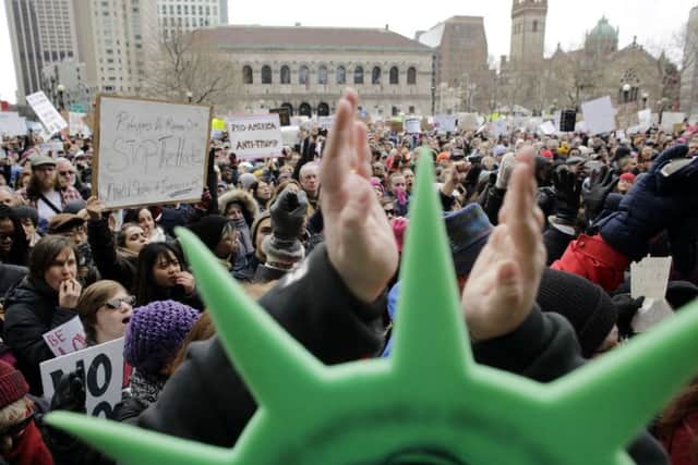 A demonstrator wears a Statue of Liberty hat and applauds during a rally against President Trump's order that restricts travel to the U.S., Sunday, Jan. 29, 2017, in Boston. (AP Photo/Steven Senne)