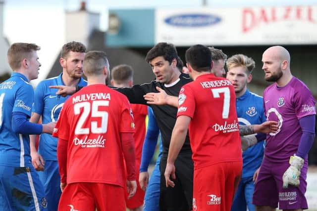 Referee Andrew Davey is surrounded by Portadown and Loughgall players