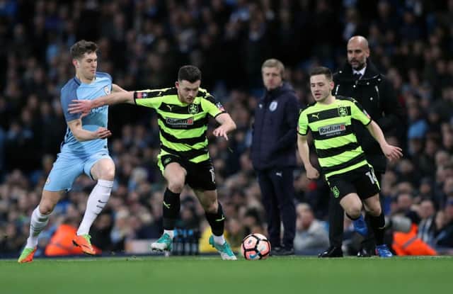 Manchester City's John Stones (left) and Huddersfield Town's Harry Bunn battle for the ball during the Emirates FA Cup replay match at the Etihad Stadium. (Photo: Martin Rickett/PA Wire.)