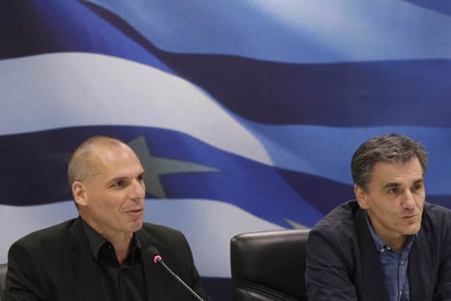 Yanis Varoufakis, left, speaks as he was handing over to the new Greek Finance Minister Euclid Tsakalotos in Athens on July 6, 2015 (AP Photo/Petr David Josek)
