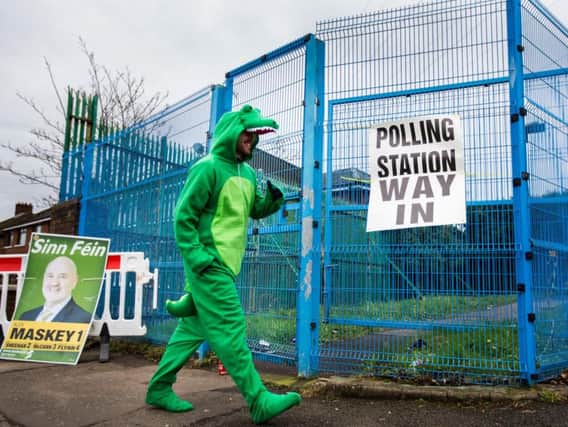 Irish language activist Dominic Sherry walks into a West Belfast polling station dressed in a crocodile costume to cast his vote in the Northern Ireland Assembly elections.