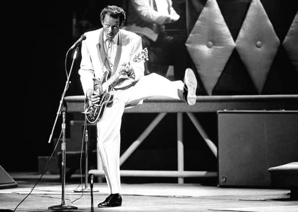 In this April 4, 1980 file photo, guitarist and singer Chuck Berry performs his "duck walk" as he plays his guitar on stage