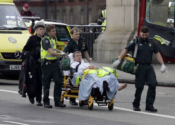 Emergency services transport an injured person to an ambulance, close to the Houses of Parliament in London, Wednesday, March 22, 2017.  (AP Photo/Matt Dunham)