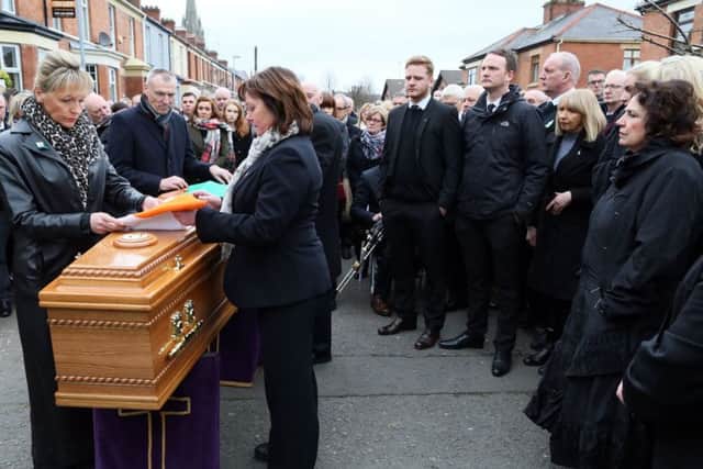 Martin McGuinness's widow Bernie (far right) watches as an Irish tricolur is placed on his coffin outside his home in the Bogside