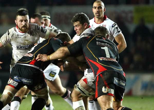 Sean Reidy of Ulster is tackled by Lewis Evans(L) and Sam Hobbs of Dragons