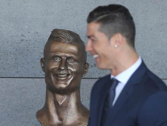 Cristiano Ronaldo stand next to a bust of the player at the Madeira international airport
