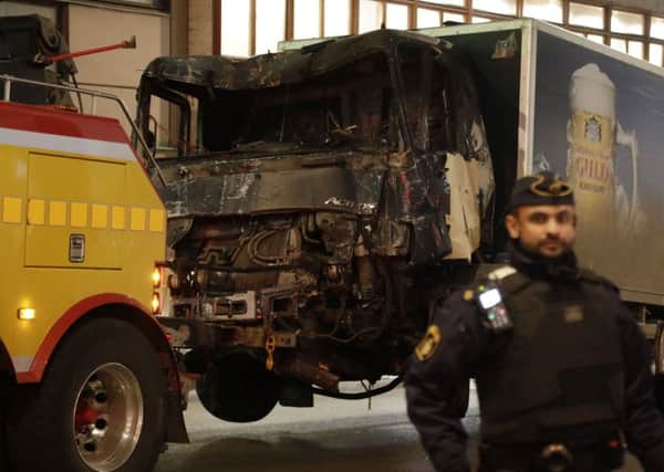A destroyed truck is pull away by a service car after it was driven into a department store in Stockholm, Sweden, Saturday, April 8, 2017.  (AP Photo/Markus Schreiber)