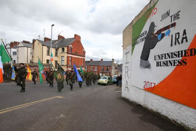 A republican parade on Easter Monday passes a Bogside mural praising the IRA