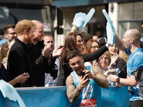 The Duke and Duchess of Cambridge and Prince Harry urges on runners at the Head Together cheering point during the Virgin Money London Marathon in Blackheath.