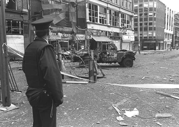 An RUC man looks out at the scene of a bombing against a UDR Land Rover in Belfast city centre in February 1987.