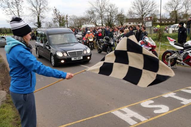 A chequered flag is waved as the hearse carrying the coffin of Italian rider Dario Cecconi crosses the finish line during a lap of honour at the Tandragee 100 circuit.