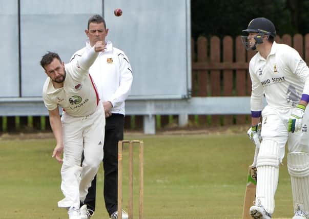 Phil Eaglestone bowling for Waringstown against Instonians, watched by Nikolai Smith and umpire Michael Foster