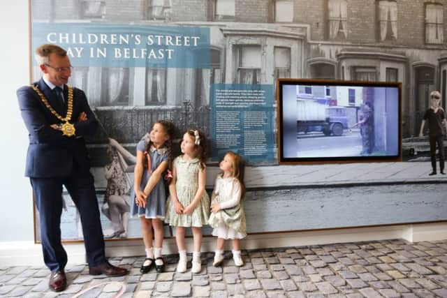 Lord Mayor Alderman Brian Kingston re-enacts an old Belfast street scene with Cara, Ava and Riona Gallagher during the opening of Belfast City Halls new Â£1.3 million exhibition.
