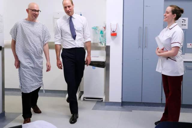 The Duke of Cambridge escorts patient Simon, left, into a radiotherapy treatment room during a visit to the Royal Marsden NHS Foundation Trust