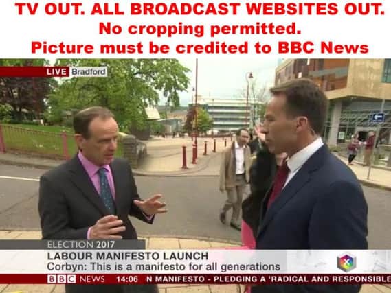 Video grab taken from BBC News of BBC assistant political editor Norman Smith (left) talking to BBC reporter Ben Brown, who is slapped on the shoulder after he moved a passer-by out of the way during a live interview