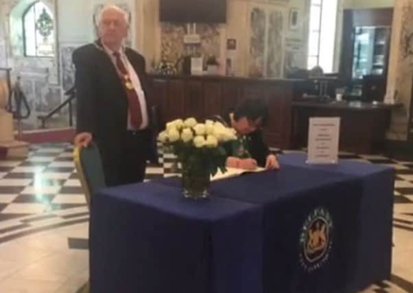 Belfast's deputy Lord Mayor opens a book of condolence at City Hall.