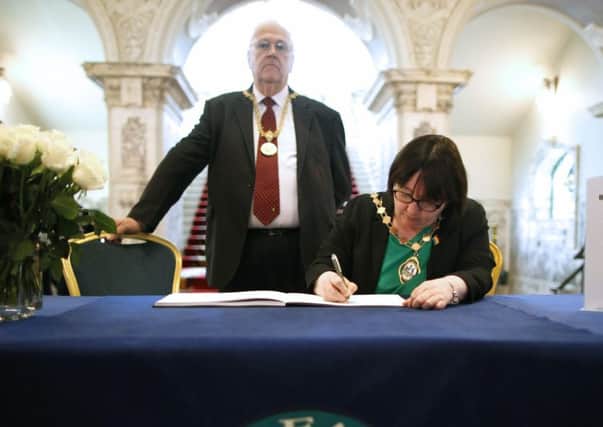 Sinn Fein's Mary Ellen Campbell signing the book, with DUP man Tom Haire behind her