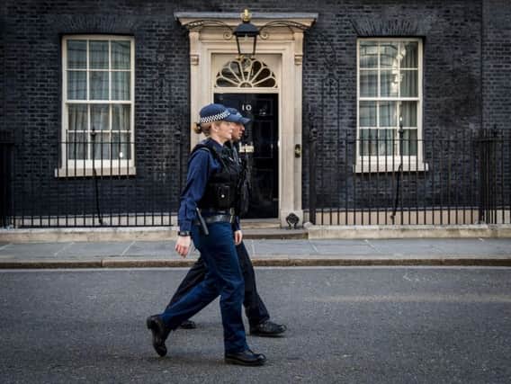 Police officers pass 10 Downing Street in London, after Scotland Yard announced armed troops will be deployed to guard "key locations" such as Buckingham Palace, Downing Street, the Palace of Westminster and embassies.