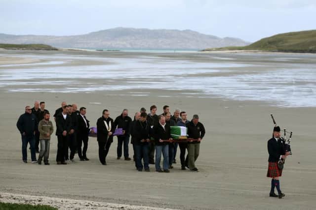 The coffin of Eilidh MacLeod draped in the Barra flag is carried across Traigh Mhor beach on Barra