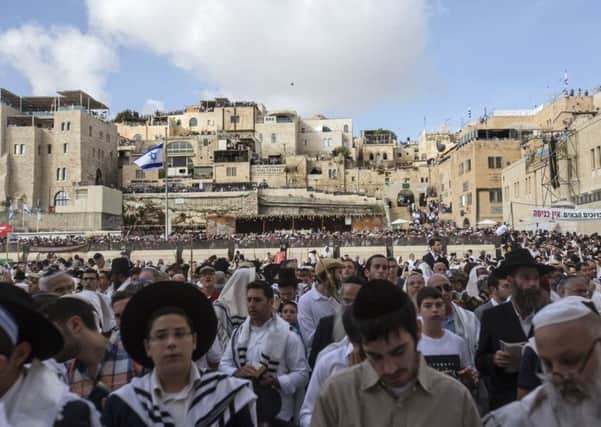 Covered in prayer shawls, Jewish men of the Cohanim Priestly caste participate in a blessing during the holiday of Sukkot, in front of the Western Wall, the holiest site where Jews can pray in Jerusalem's Old City, Wednesday, Oct. 19, 2016. The Cohanim, believed to be descendants of priests who served God in the Jewish Temple before it was destroyed, perform a blessing ceremony of the Jewish people three times a year during the festivals of Passover, Shavuot and Sukkot. (AP Photo/Tsafrir Abayov)