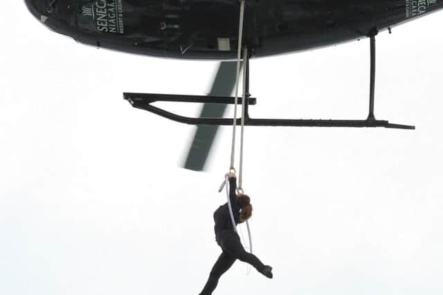 Nik Wallenda watches from above as his wife, Erendira Wallenda, hangs by her teeth while suspended from a helicopter above Niagara Falls