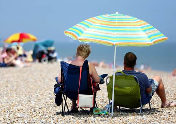 Sunbathers shelter under beach umbrellas on the seafront in Aldeburgh, Suffolk, on Sunday as Britain basked in the hottest day of the year so far
