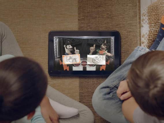 Children looking at the Buddy Thunderstruck: The Maybe Pile story on a device.