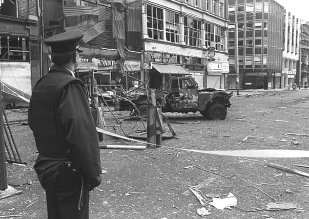 An RUC man looks at the remains of a Land Rover which was bombed in Belfast city centre in February 1987, killing two UDR soldiers