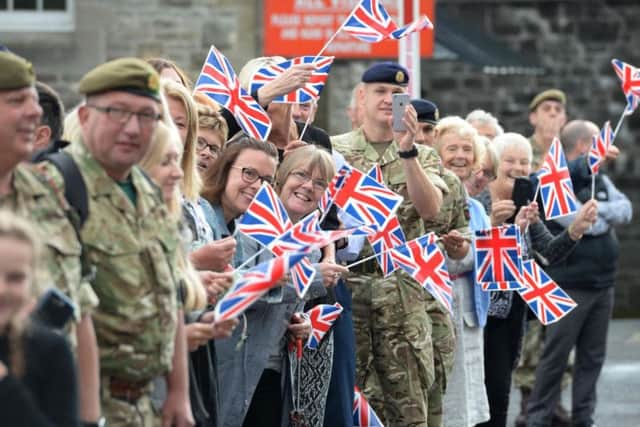 People wave flags as the Prince of Wales leaves following a tour of The Regimental Museum of the Royal Welsh, in Brecon, Wales.