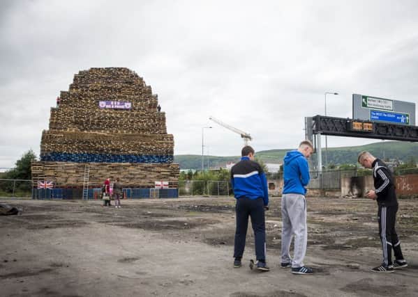 Young men play near a loyalist bonfire at Roden Street in Belfast. Police in Northern Ireland have warned their resources could be stretched amid growing fears of tension around the burning of Eleventh night bonfires. Photo: PA Wire
