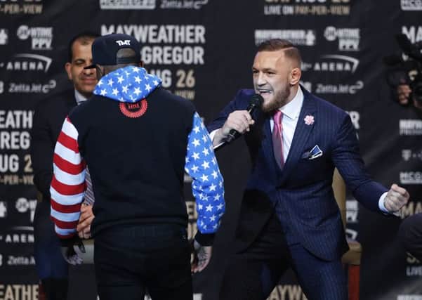 Conor McGregor, right, taunts as Floyd Mayweather Jr. walks back to the podium
