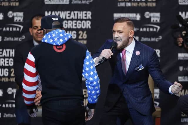 Conor McGregor, right, taunts as Floyd Mayweather Jr. walks back to the podium